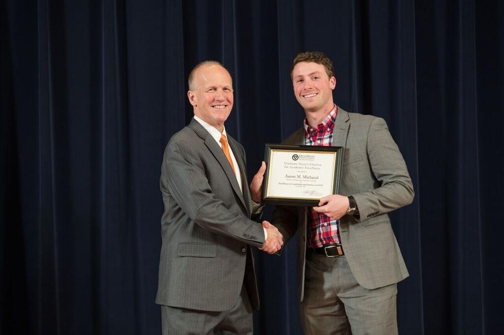 Doctor Potteiger posing for a photo with an award recipient in a grey suit and a red plaid shirt